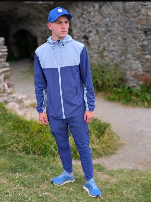 Man wearing Makalu Two-Tone Blue/Navy Blue activewear tracksuit and blue cap outdoors near stone ruins
