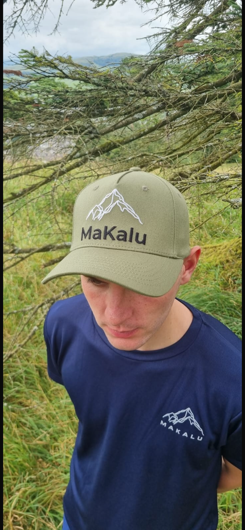 MaKalu 5 panel cap in exclusive forest green with mountain logo, worn outdoors